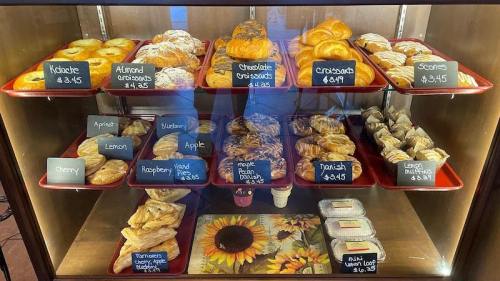 A display case filled with various pastries, including croissants, danishes, and scones, with price tags visible.