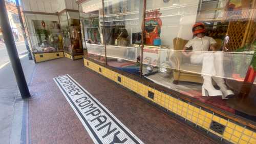 A storefront with a vintage display, featuring a mannequin in white attire and retro decor. "Company" is tiled on the floor.