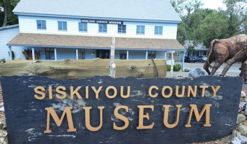 Sign for Siskiyou County Museum in front of a building with a blue exterior and a brown roof.