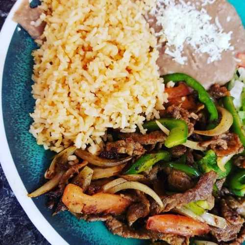 A colorful plate featuring seasoned beef with peppers and onions, rice, refried beans, and cheese.