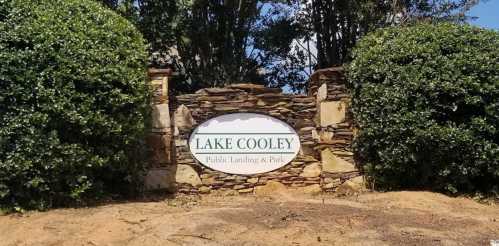 Sign for Lake Cooley Public Landing & Park, framed by stone and greenery.