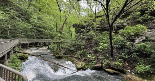 a boardwalk along a rushing river at spring mill state park in indiana