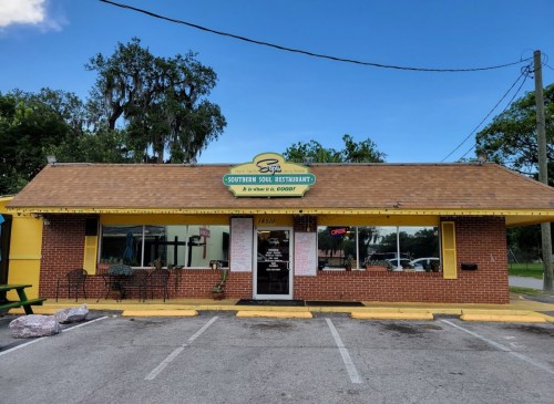 A brick restaurant with a yellow exterior and a sign reading "Southern Soul Restaurant," surrounded by trees and a blue sky.