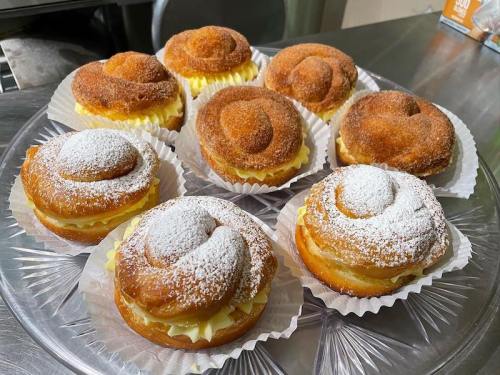 A platter of freshly baked pastries, some topped with powdered sugar and others with a cinnamon sugar coating.