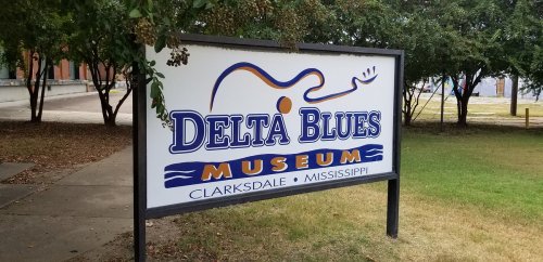 Sign for the Delta Blues Museum in Clarksdale, Mississippi, featuring a guitar graphic and colorful text.