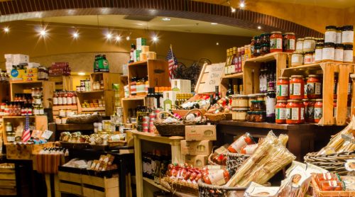 A vibrant market display filled with jars, bottles, and baskets of various gourmet foods and condiments.