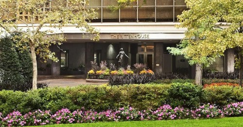 Exterior view of The Rittenhouse with a statue and colorful flower beds in the foreground.