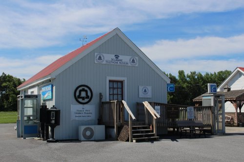Exterior of the Delaware Telephone Museum, featuring a wooden building with a red roof and signage.