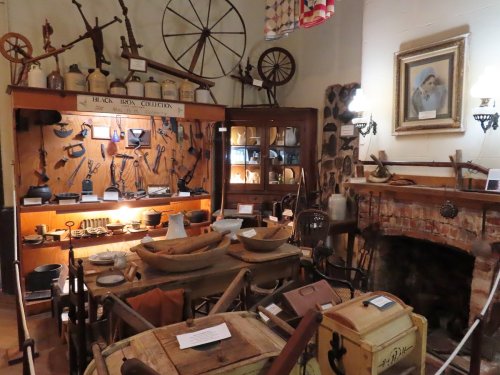 A vintage display of various antique tools and household items in a rustic museum setting.