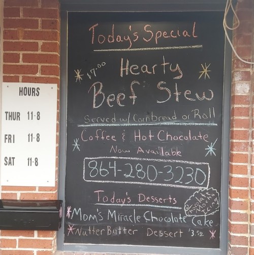 Chalkboard menu displaying today's special: hearty beef stew, desserts, and contact info. Hours listed on the side.