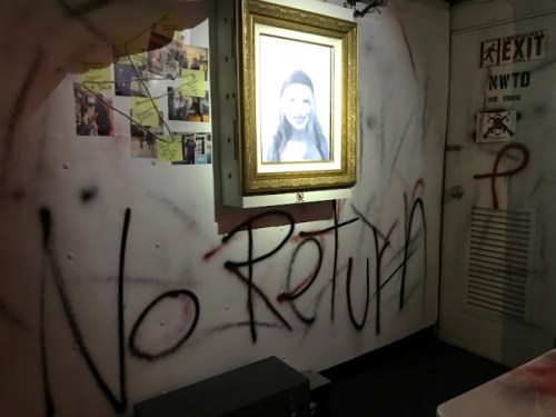 A dimly lit room with a framed portrait and graffiti reading "No Return" on the walls.
