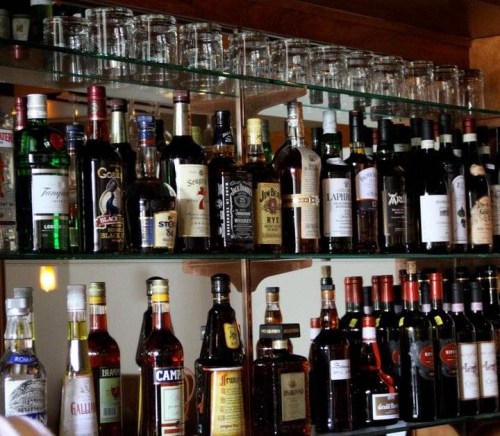 A well-stocked bar featuring various bottles of liquor and spirits on glass shelves.