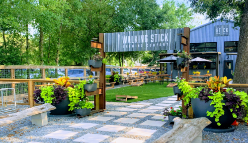 Outdoor seating area at Walking Stick Brewing Company, featuring greenery, planters, and a welcoming entrance.