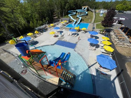 Aerial view of a water park featuring slides, pools, and colorful umbrellas around lounge chairs.