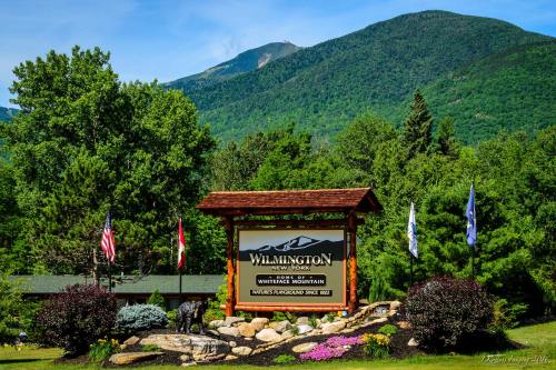 Sign for Wilmington, New York, with Whiteface Mountain in the background and flags displayed in front.