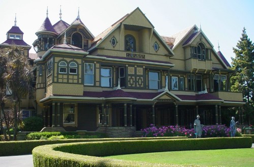 The Winchester Mystery House, a large Victorian mansion with intricate architecture and lush gardens.