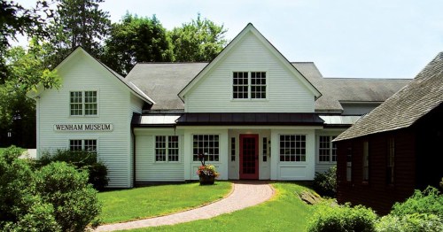 Exterior view of the Wenham Museum, featuring a white building with a red door and landscaped surroundings.