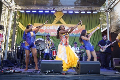 A vibrant performance on stage with dancers in colorful outfits and a live band playing in the background.