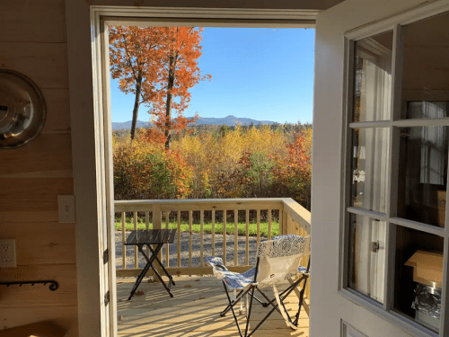 A view from an open door showcasing a colorful autumn landscape with trees and mountains in the distance.