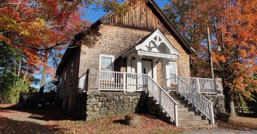A wooden building with a porch, surrounded by colorful autumn trees, labeled "Londonderry Grange, Vt."