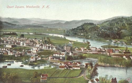 A vintage postcard view of Court Square in Woodsville, NH, showcasing a river, hills, and quaint buildings.