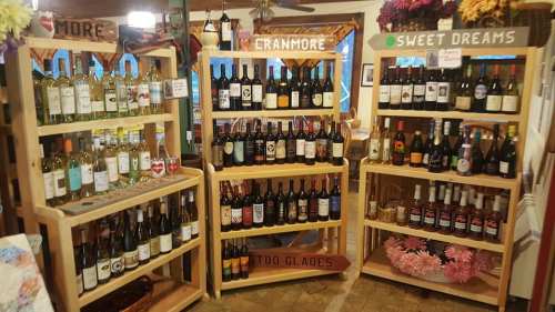 Shelves filled with various bottles of wine and spirits, labeled "Cranmore" and "Sweet Dreams," in a cozy setting.