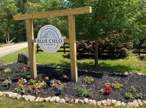 Sign for Blue Cielo Farms surrounded by flowers and greenery, located near Lake Russell.