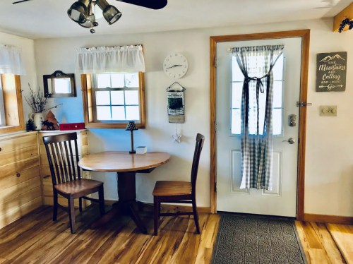 Cozy interior with a wooden table and chair, a door with a curtain, and decorative wall elements.