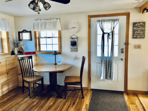 Cozy interior with a wooden table and chair, a door with a curtain, and decorative wall elements.