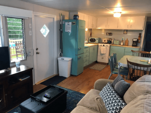 A cozy kitchen and living area featuring a retro blue fridge, dining table, and comfortable sofa.