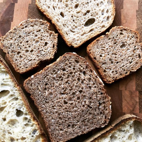 Sliced brown bread on a wooden cutting board, showcasing a variety of textures and crusts.