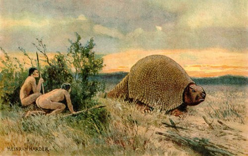 Two prehistoric humans observe a large, armored creature in a grassy landscape at sunset.