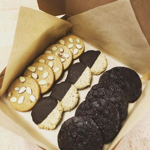 A box of assorted cookies: almond-topped, half-dipped in chocolate, and dark chocolate cookies.
