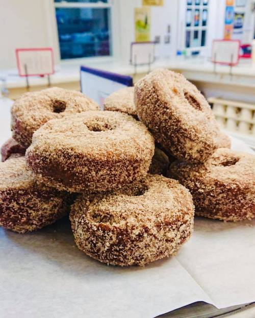 A stack of cinnamon sugar-coated donuts on a white paper surface.