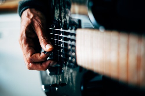 A close-up of a hand playing the strings of an electric guitar.