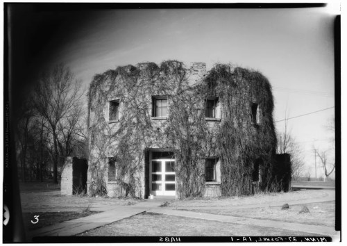 A round, ivy-covered building with large windows, surrounded by bare trees and a clear sky.