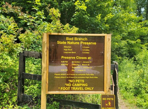 Sign at Bad Branch State Nature Preserve with trail distances, hours, and rules for visitors. No pets or camping allowed.