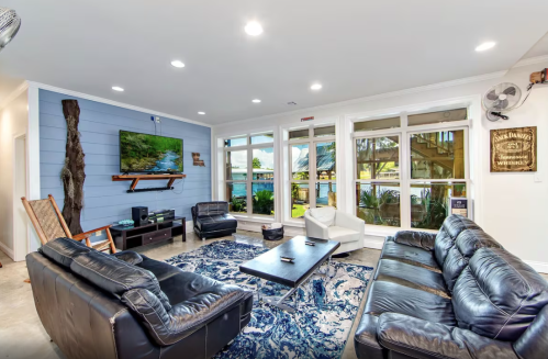 Modern living room with leather sofas, a coffee table, a TV, and large windows overlooking a scenic view.