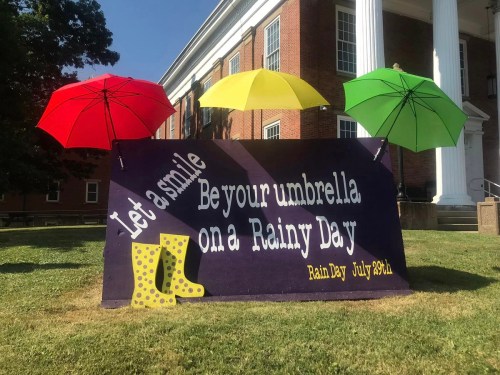 A colorful banner with umbrellas and rain boots, promoting a "Rain Day" event on July 29th.