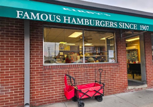 Exterior of Kirby's Famous Hamburgers since 1907, featuring a red wagon in front of the brick building.