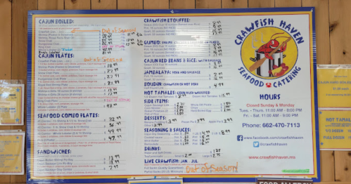 Menu board for Crawfish Haven featuring seafood dishes, prices, and hours of operation. Some items marked as out of season.