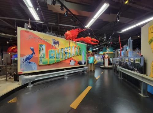 Colorful exhibit featuring a "Greetings from Louisiana" sign, with a large lobster and various Louisiana-themed decorations.