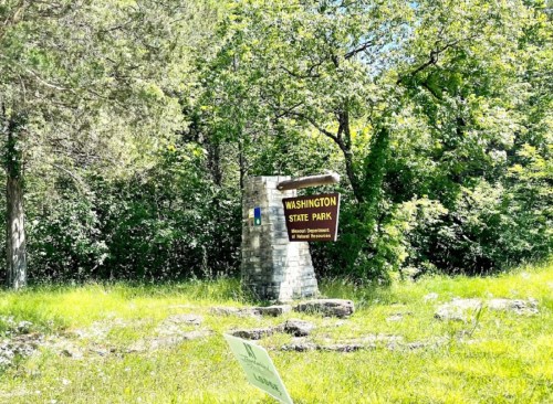 Sign for Washington State Park surrounded by lush greenery and trees on a sunny day.