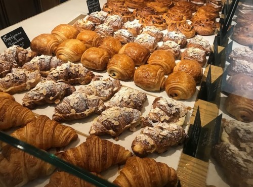 A display of various pastries, including croissants and cinnamon rolls, arranged neatly in a bakery case.