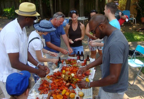 A group of people enjoying a seafood boil outdoors, sharing food and drinks at a lively gathering.