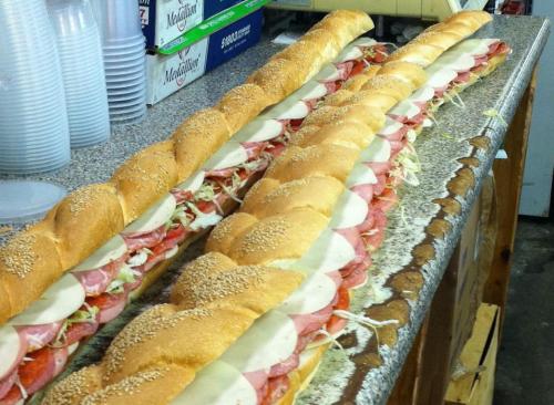 A long sandwich filled with layers of meats, cheese, and vegetables, resting on a countertop.