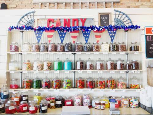 A colorful candy display with jars of various sweets, decorated with red, white, and blue bunting.