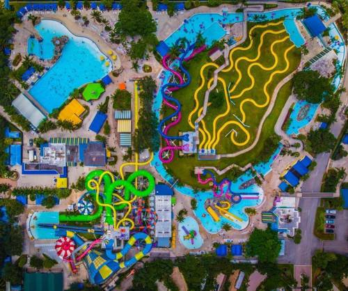 Aerial view of a vibrant water park featuring pools, water slides, and lush greenery.