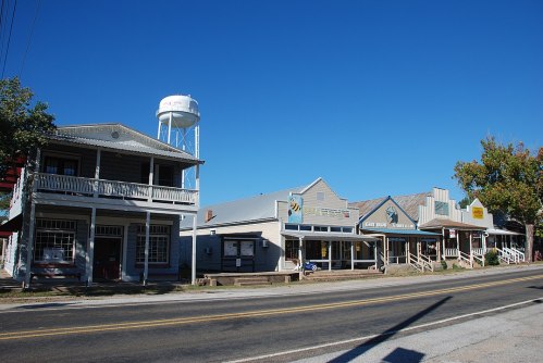 A small town street featuring historic buildings, a water tower, and a clear blue sky.