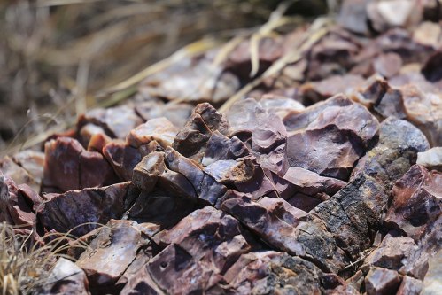 Close-up of a textured surface of colorful, jagged rocks with earthy tones and scattered grass.